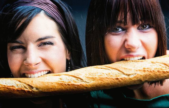 2 jeunes femmes mordent dans la même baguette de pain