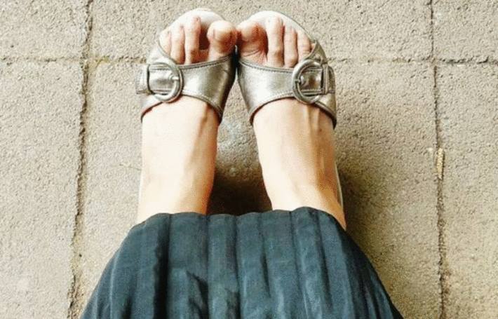 sur un sol ciment ou béton des pieds de femme chaussées de sandales argent