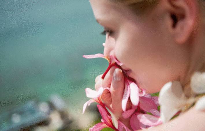 une femme respire le parfun des fleurs roses