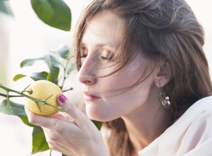 une femme respire l'odeur d'un citron