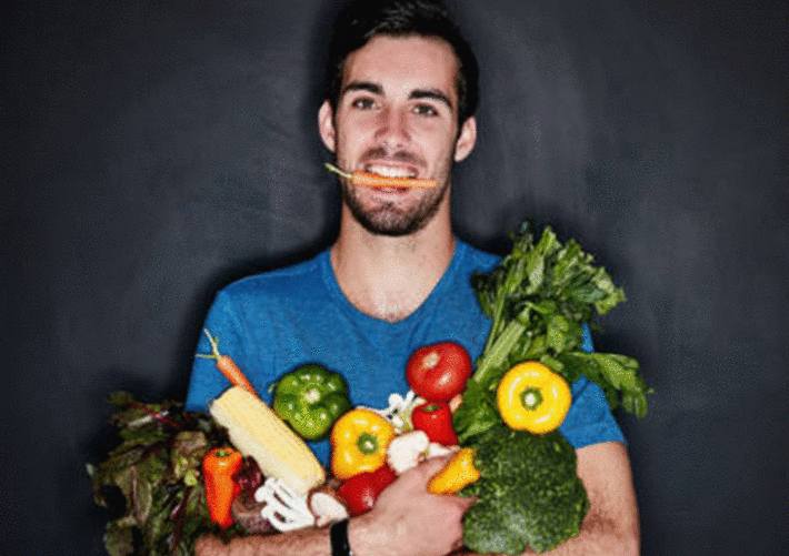 homme-tenant-un-bouquet-de-légumes-avec-une-carotte-entre-les-dents