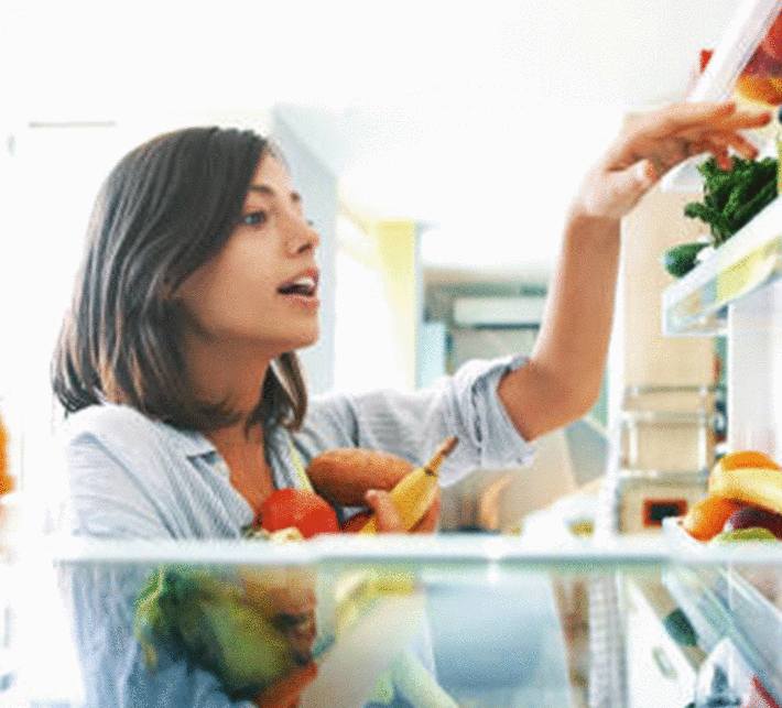 jeune-femme-brune-choisissant-des-légumes-dans-la-porte-du-réfrigérateur