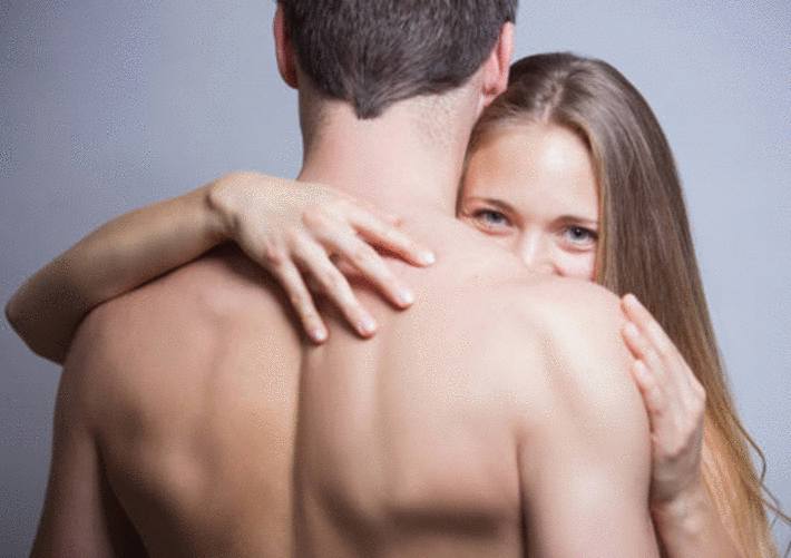 une jeune femme de face nue entoure de son bras un homme nu de dos