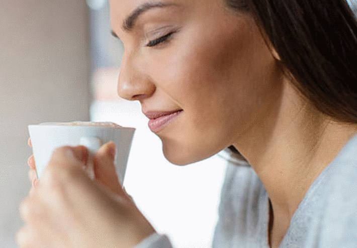 une femme boit un café dans le but de maigrir